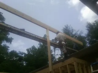 Carpenter setting a ridge beam over a new addition frame — Ice Dam Removal by Roofing Brothers in Willseyville