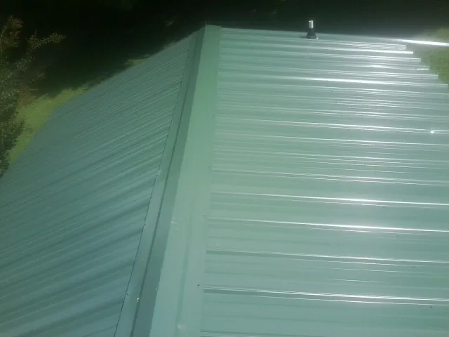 New green metal panels meeting at the ridge of a roof — Flat Roof Repair work by our crew in Willseyville