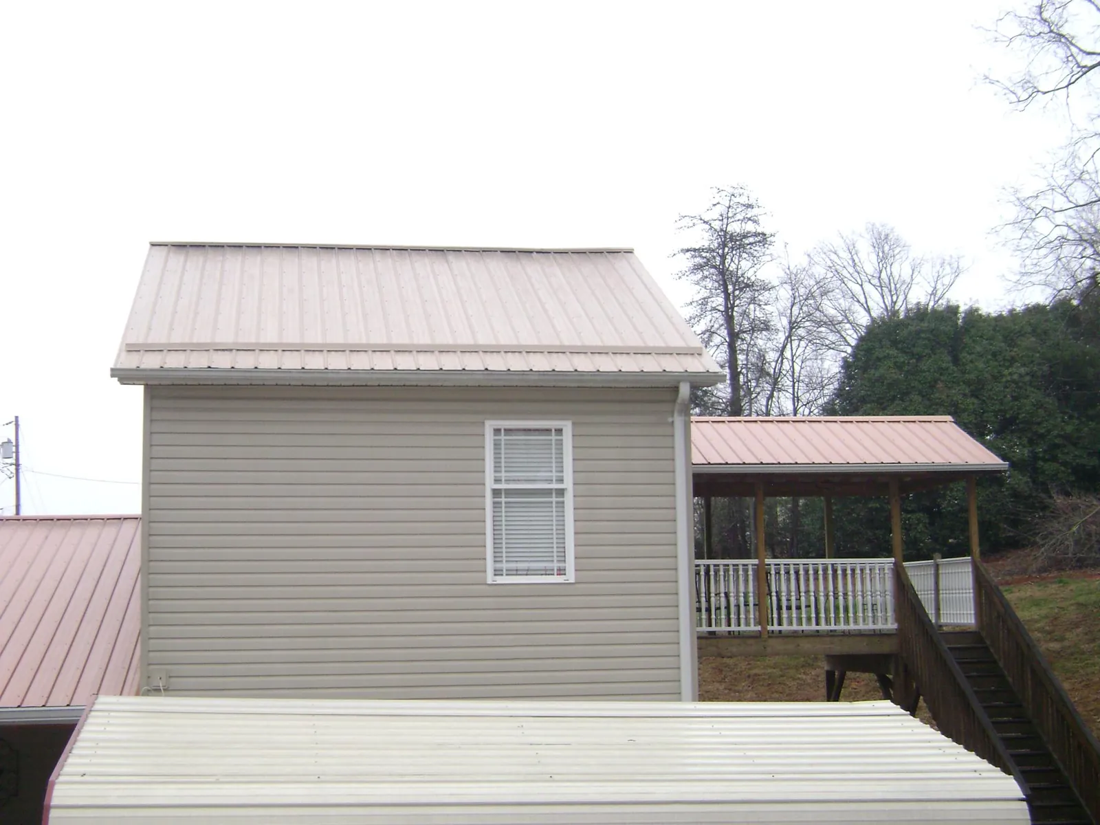 Tan metal roofs on a two story addition and attached porch, from a Roof Replacement job in Willseyville