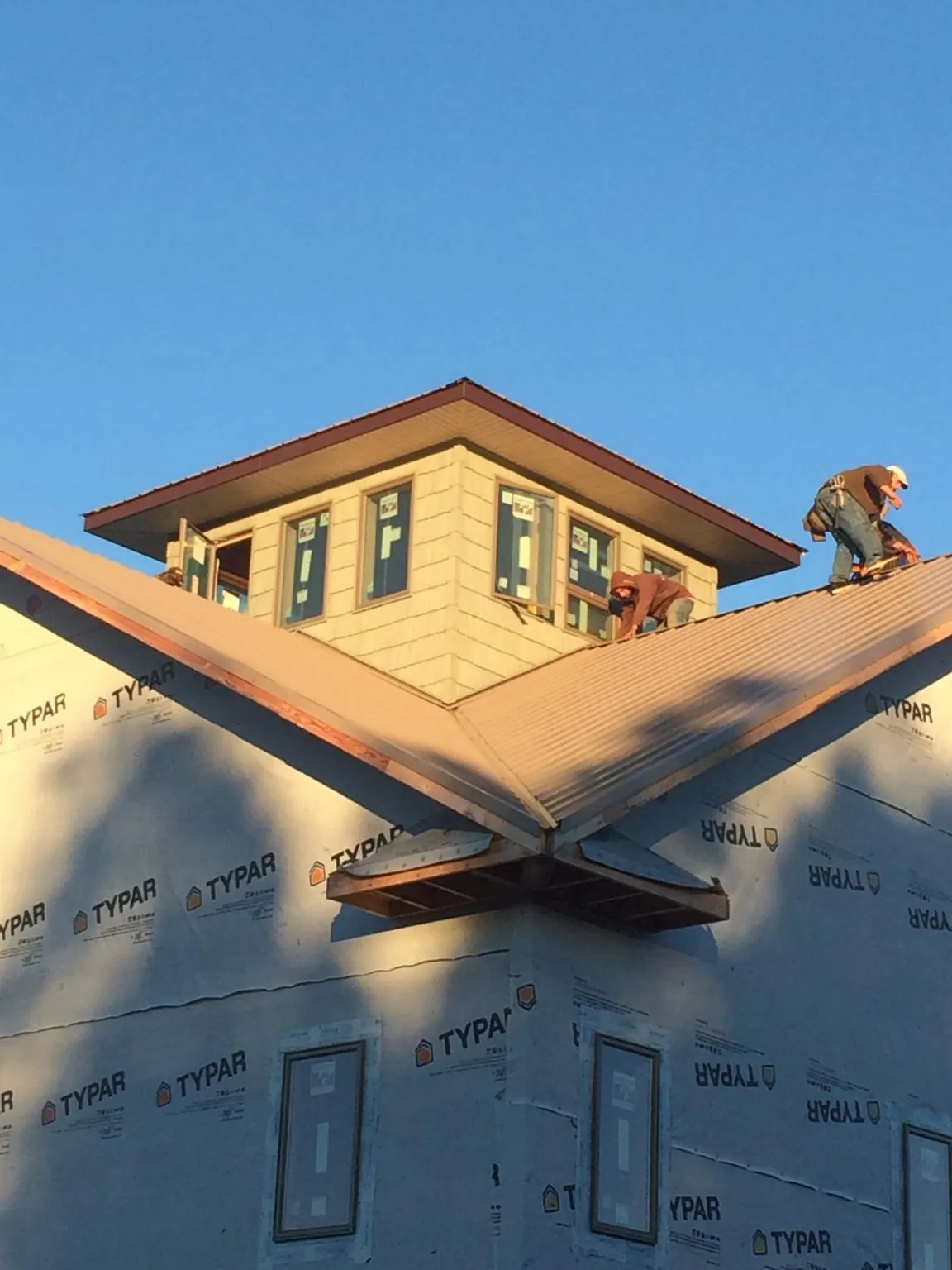 Roofers working around a rooftop cupola on a new metal roof at sunset — Roof Waterproofing in Willseyville by Roofing Brothers